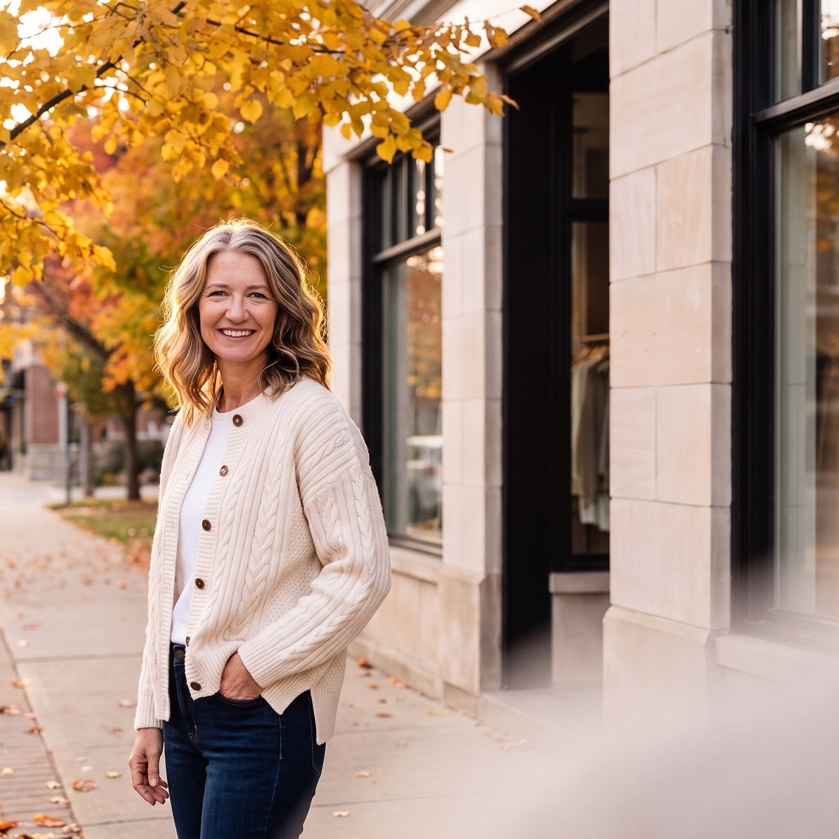 Mae standing under a golden linden tree in front of the Linden & Mae boutique